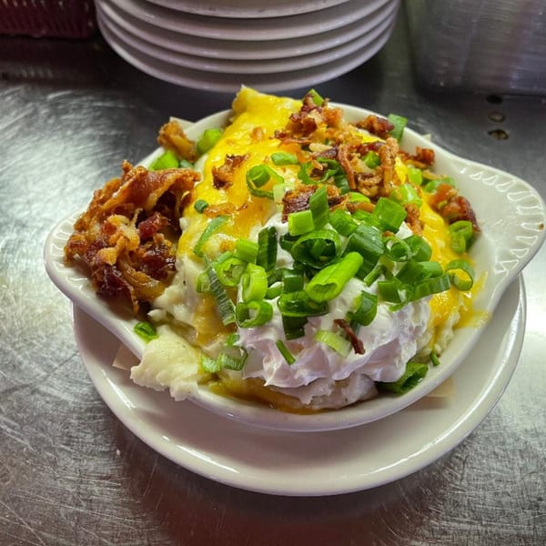 Loaded mashed potatoes topped with melted cheese, crispy fried onions, sour cream, and green onions.